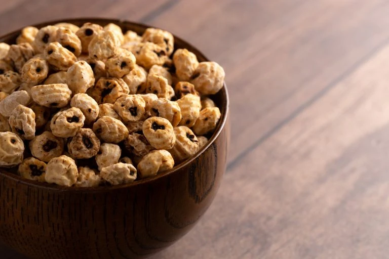 Whole tiger nuts in a wooden bowl on a warm wooden table